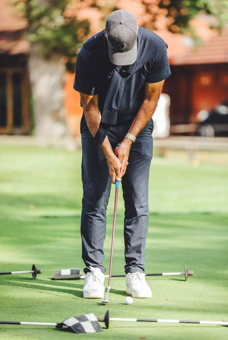 Golfer mid-putt on the practice green