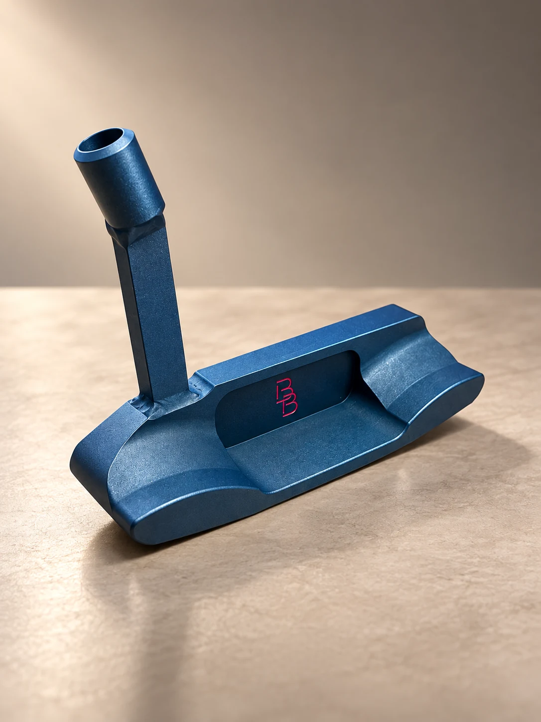 Navy Bertie Boucher putter with pink BB logo on a warm stone surface