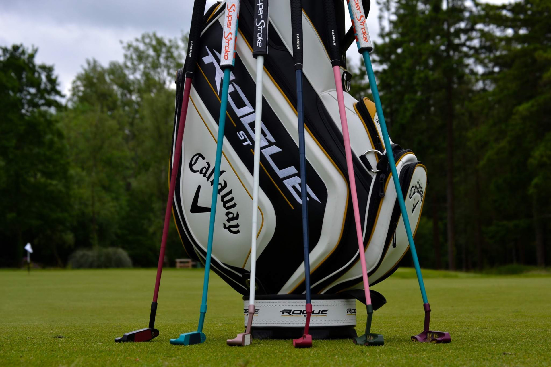 Callaway golf bag on the putting green with six Bertie Boucher putters lined up in front