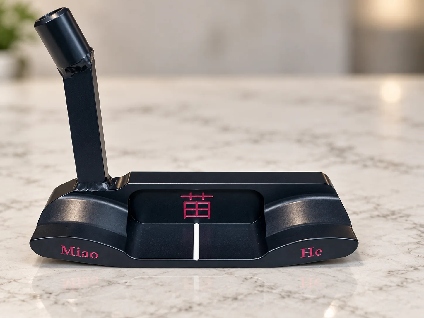 Black bespoke putter with red Miao and He engraving on a marble surface