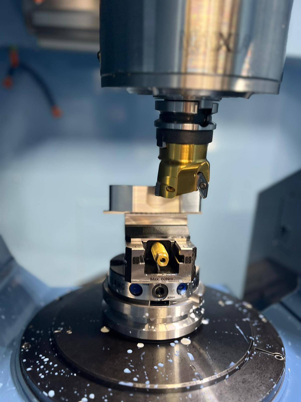 Close-up of gold-coated milling cutter over a clamped workpiece